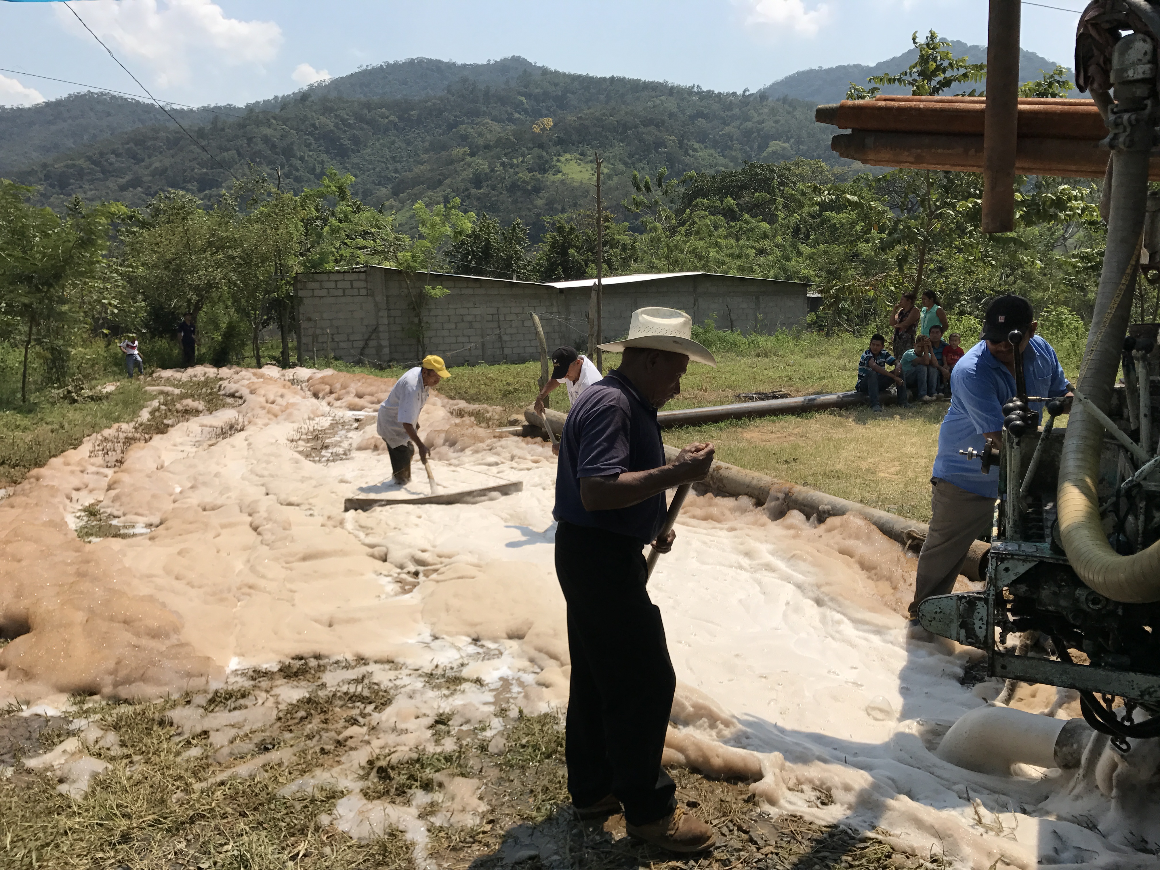 local residents help to clear away debris as the well is being drilled